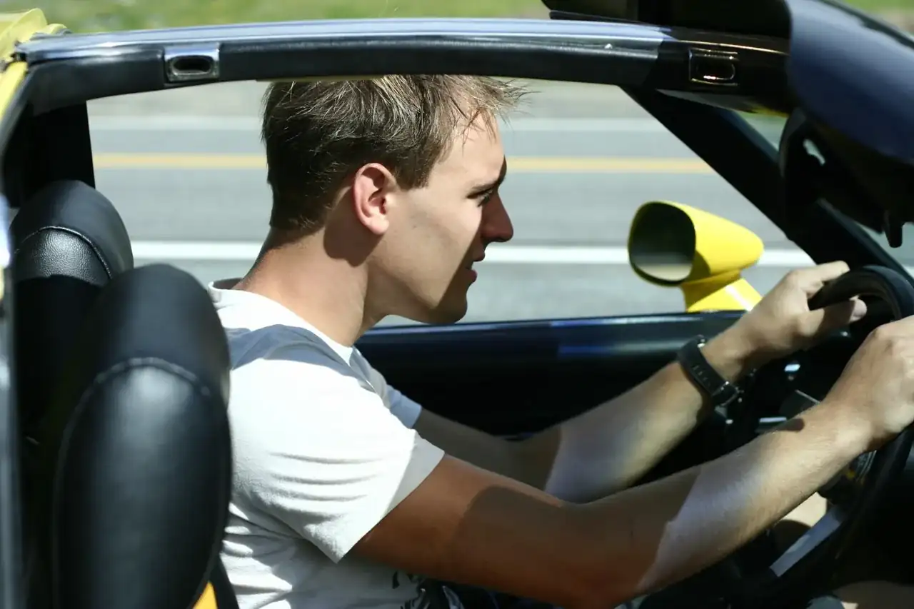 Driving a yellow C3 Corvette with the roof off on a sunny road