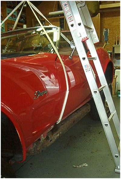 Lift straps hooked onto the rocker channels ahead of the door
