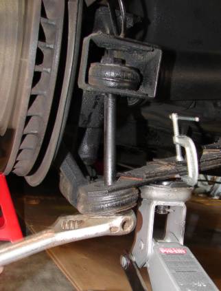 Jack under the rear spring bolt with a C-clamp on the spring